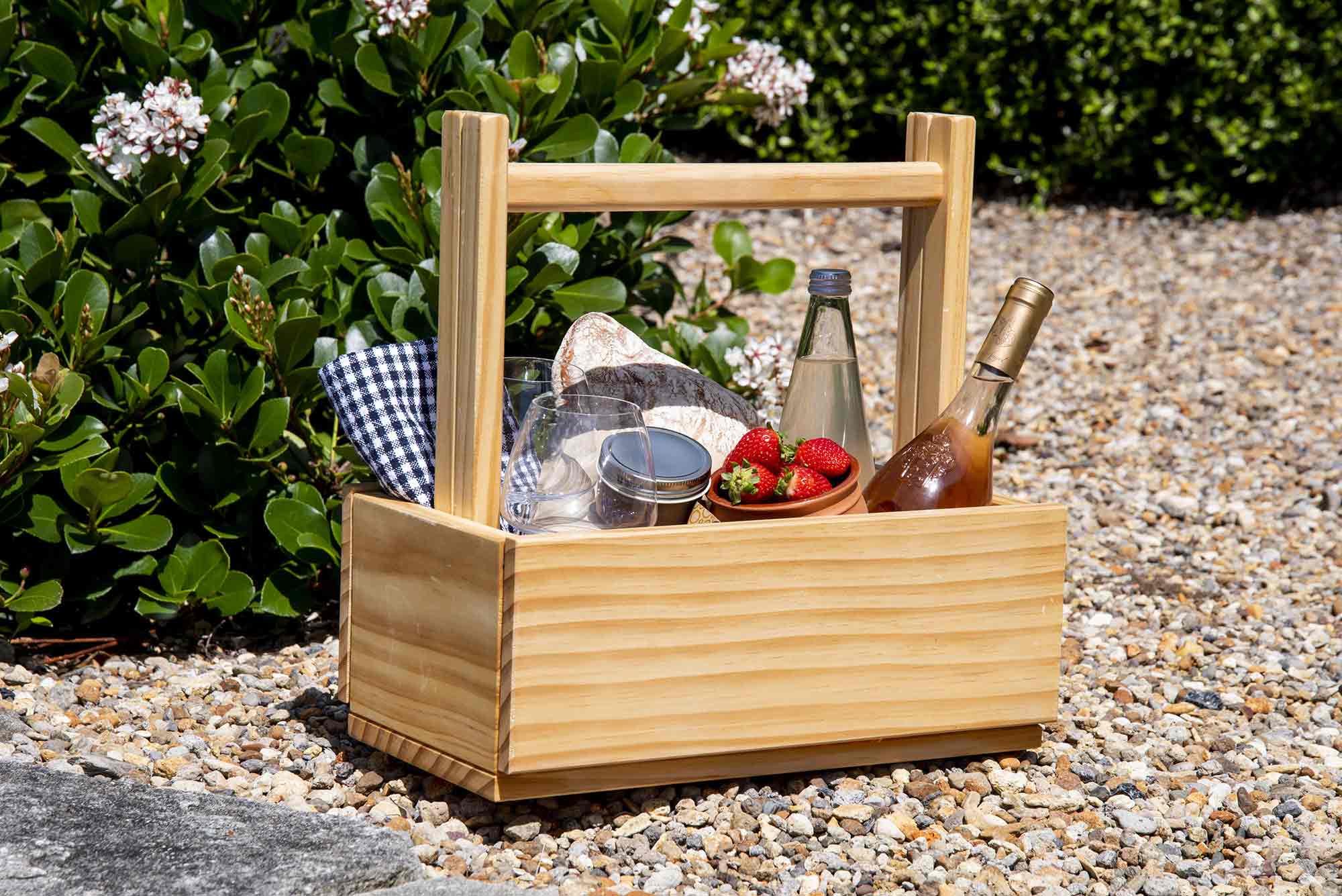 Wooden picnic basket with food and drinks on a pebbled surface. Victoria James Home Storage Box VJA Convertible