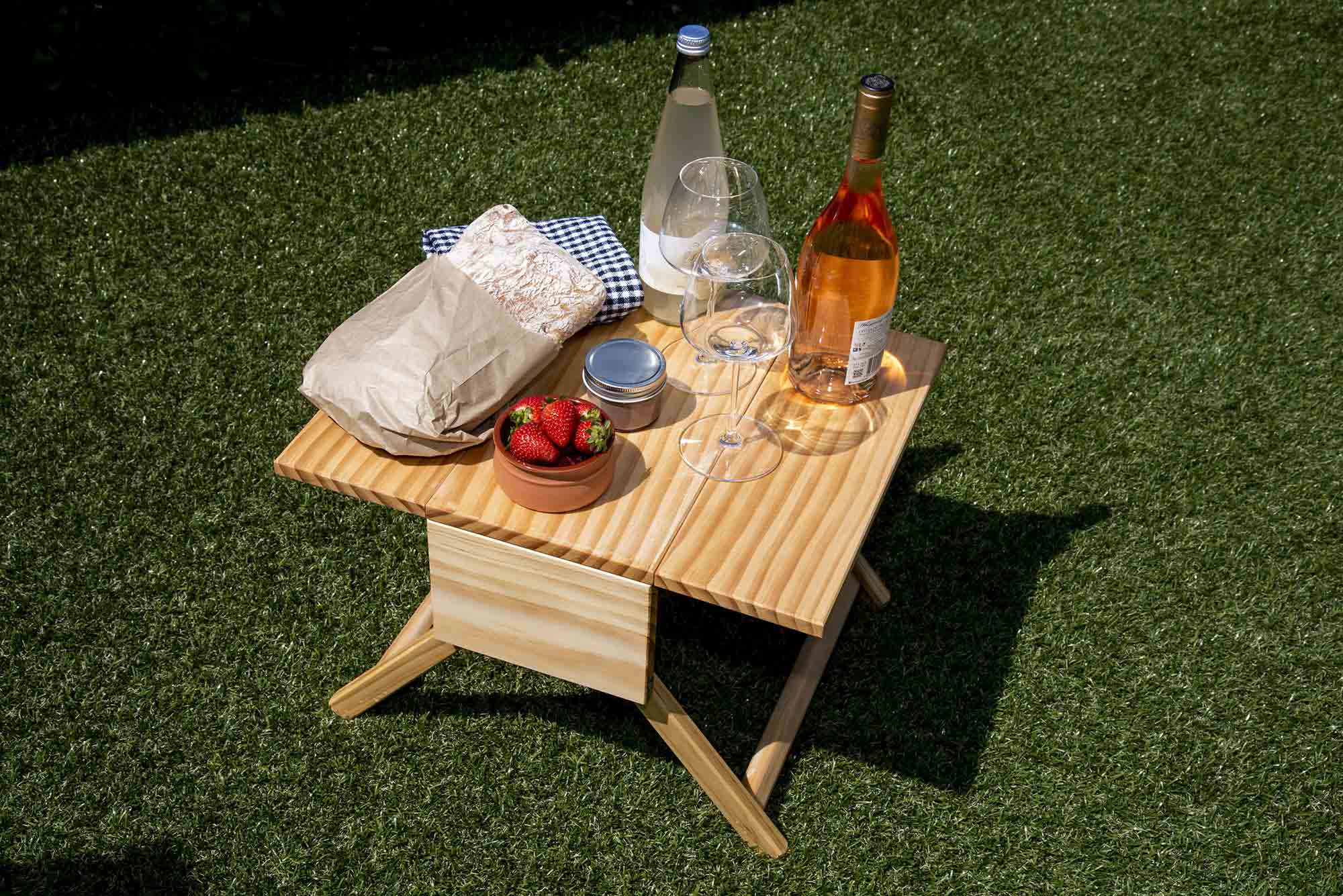 Small wooden table with food and drinks on a grassy surface. Victoria James Home Storage Box VJA Convertible