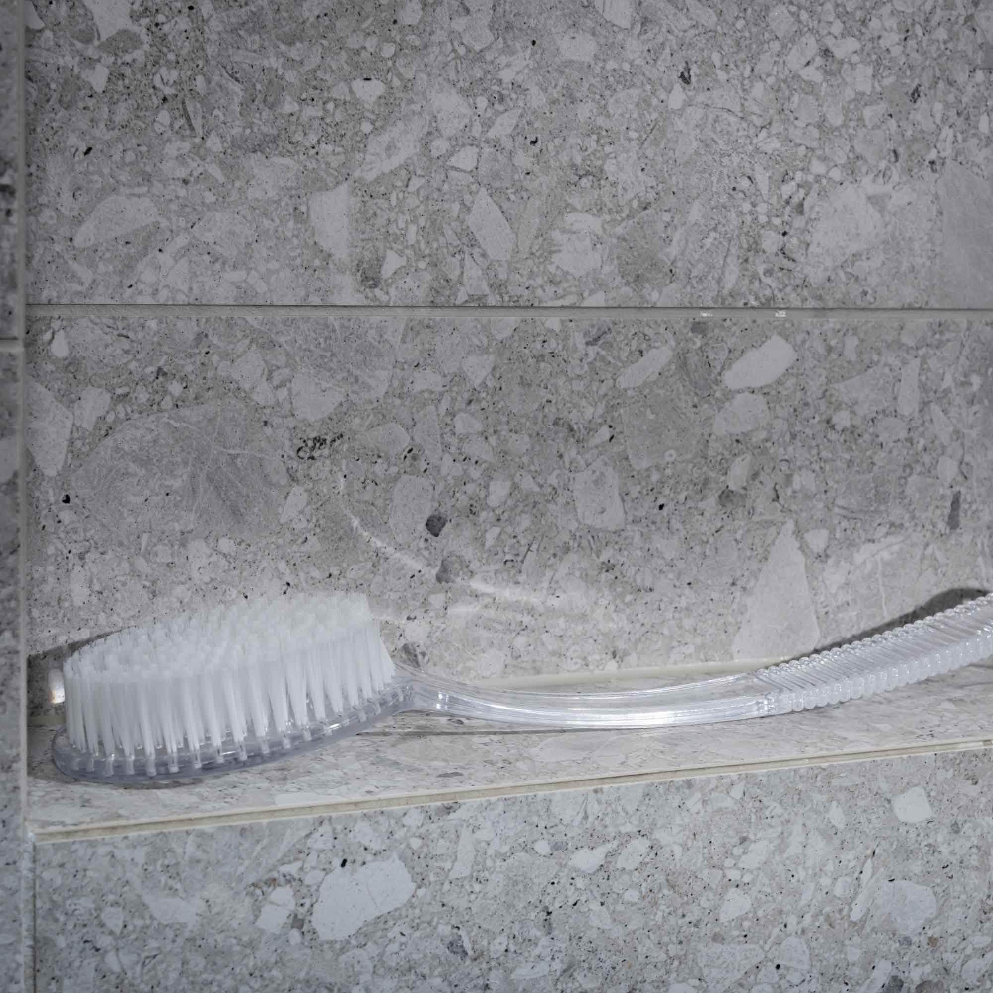 Cleaning brush on a gray tiled wall. Victoria James Body Bath & Shower Brush