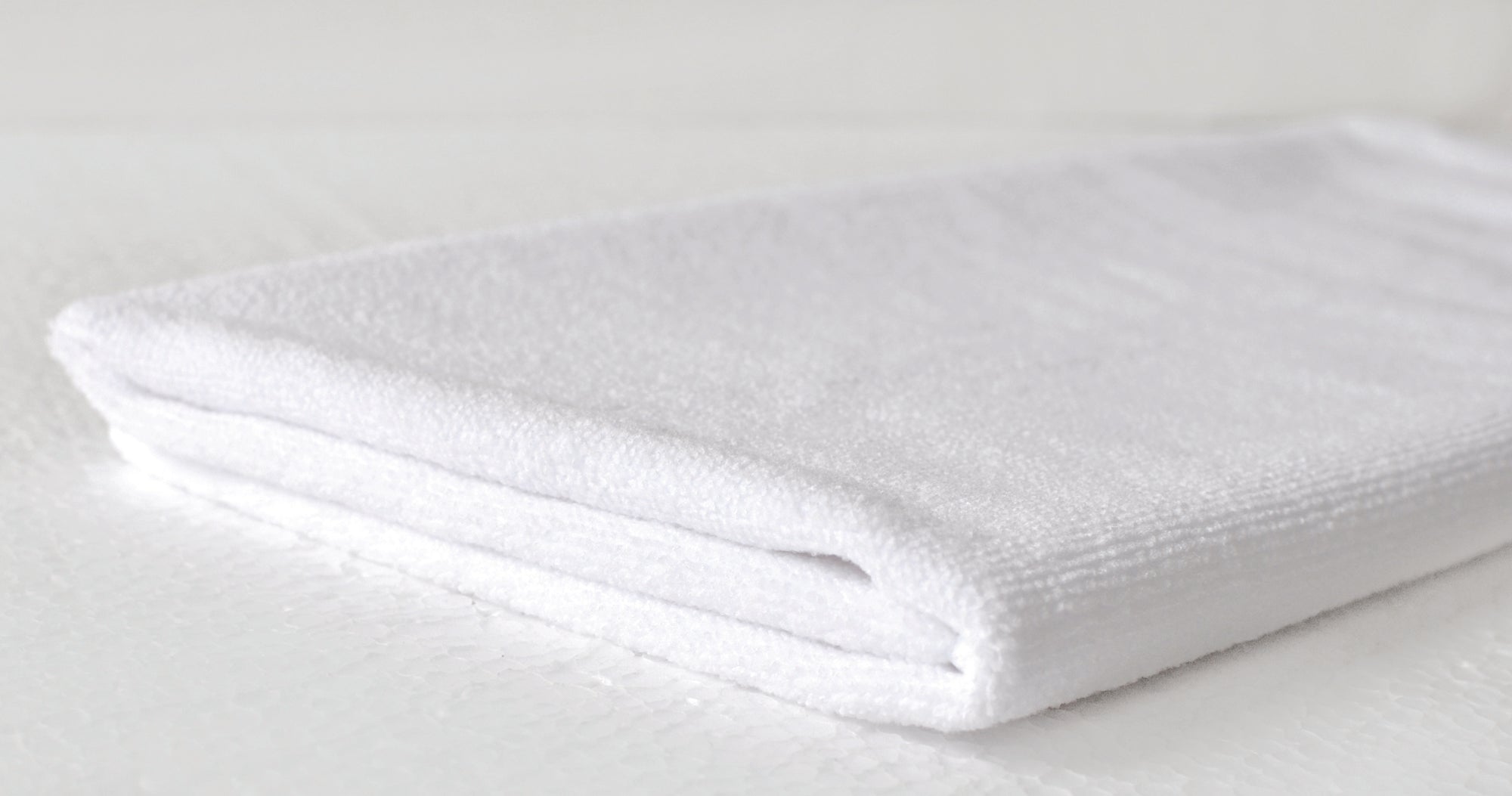 Folded white towel on a light gray background. Simply Clean Active Gym Towel