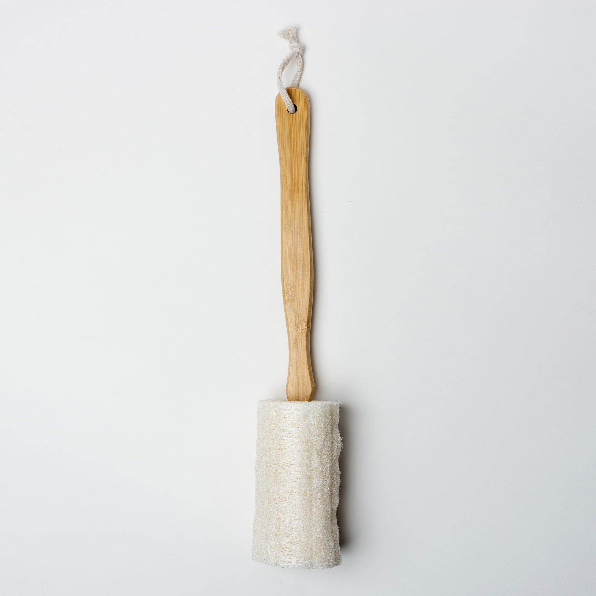 Long-handled scrub brush with a wooden handle and white bristle head on a light gray background. Victoria James Body Loofah Brush